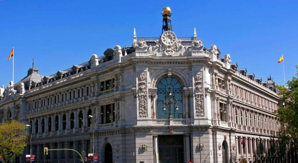 Facade of the Banco de España building, featuring ornate architectural details and a clear blue sky.