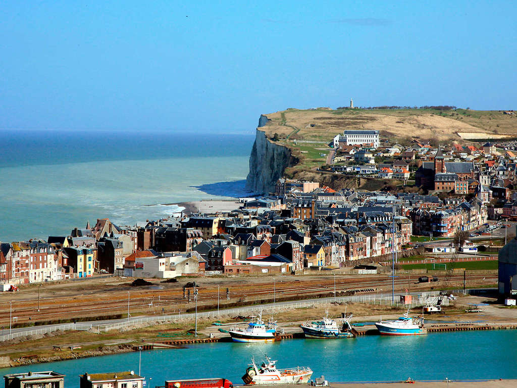 Vista panorámica de Calais, Francia, mostrando el puerto y las casas coloridas a lo largo de la costa, con acantilados en el fondo.