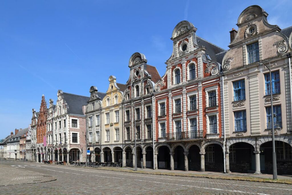 Vista de la arquitectura barroca en el casco antiguo de Arras, Francia, con casas gremiales coloridas y un cielo azul despejado.